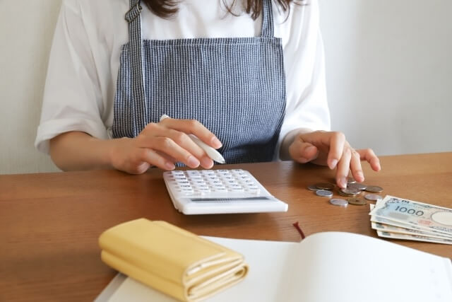 小銭を数えながら電卓を触る女性の手元