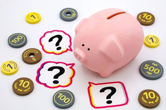 疑問を浮かべる豚の貯金箱とおもちゃの小銭