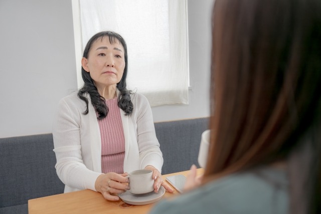 娘の話を険しい顔で聞く女性
