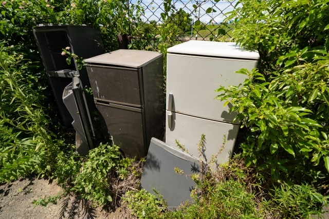 フェンス前に不法投棄された複数台の冷蔵庫