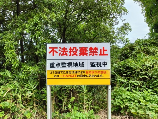 緑の中に設置された黄色の不法投棄禁止看板