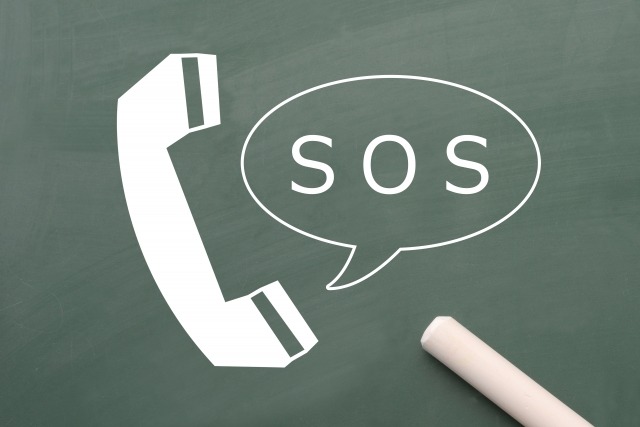 黒板に書かれたSOS吹き出しと電話アイコン