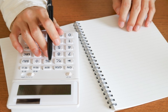 ノートを開いて電卓を触る手元