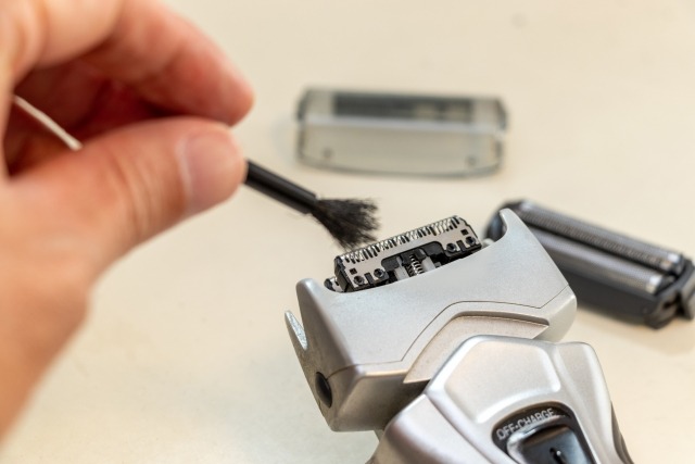 シェーバーの刃をブラシで掃除する様子