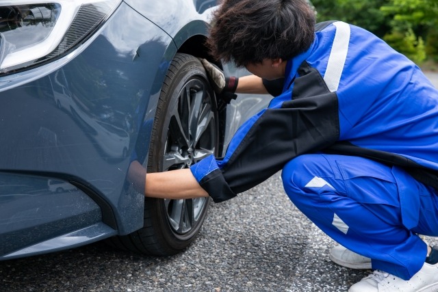 自動車のタイヤを外す作業着の男性