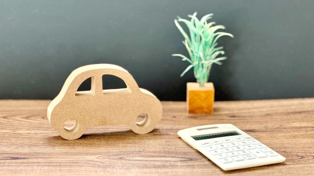 電卓と木製の車のおもちゃ