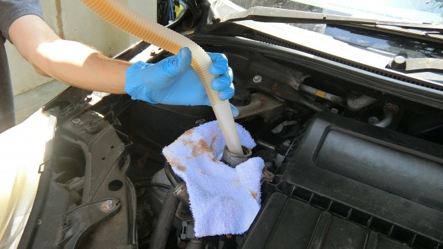 ポンプでエンジンオイルを交換する様子