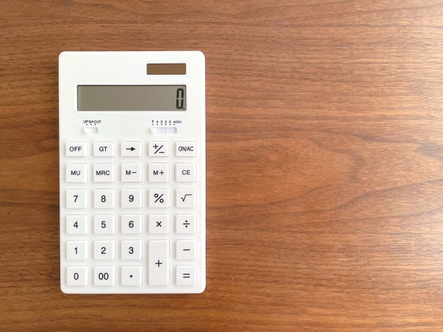 茶色のフローリングに置かれた白い電卓
