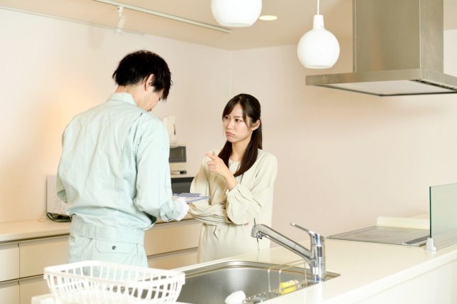 作業服の男性に指摘する女性