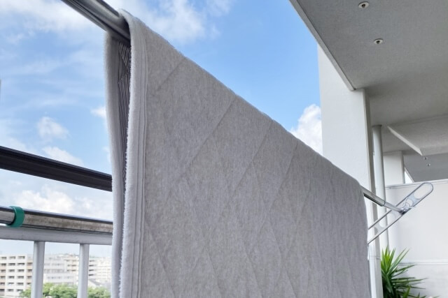 ベランダの物干し竿に干された敷きパッド