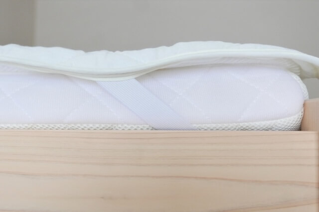 横から見たベッドに設置された白い敷きパッド
