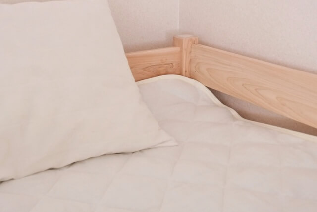 ベッドに敷かれた白い敷きパッドの角