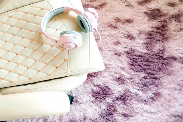 ピンクのヘッドフォンが置かれた白いゲーミングチェア