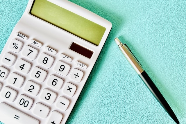 水色のデスクに置かれた電卓とペン