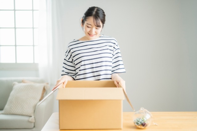 部屋で段ボール箱を開く女性