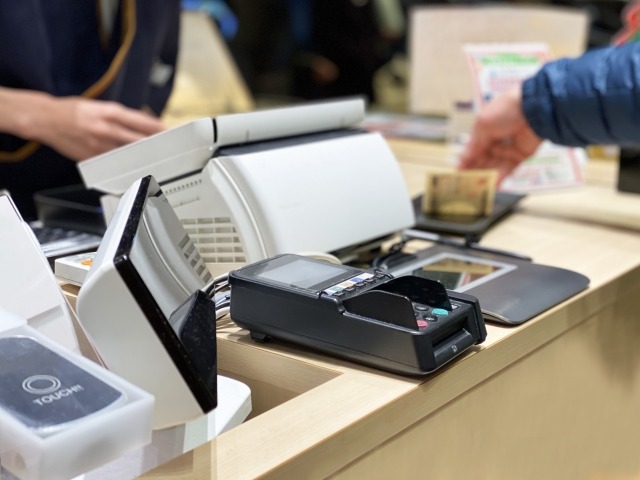 店頭レジで代金を現金で支払う様子