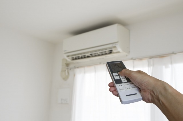 エアコンにリモコンを向ける手元