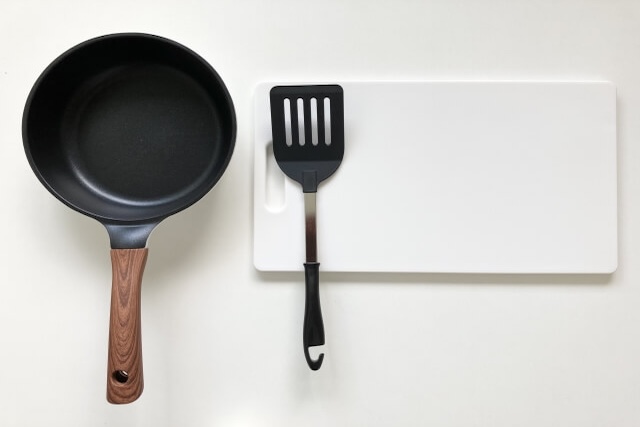 白いテーブルに並ぶフライパンとフライ返し・まな板