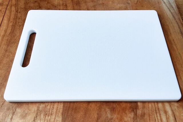 木のテーブルに置かれたプラスチック製の白いまな板