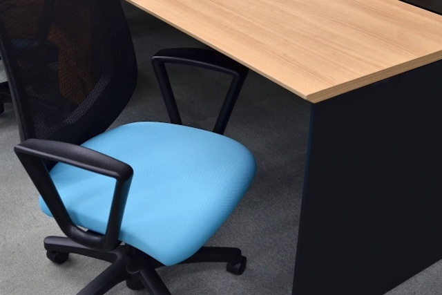 木製デスクに置かれた水色の座面のオフィスチェア