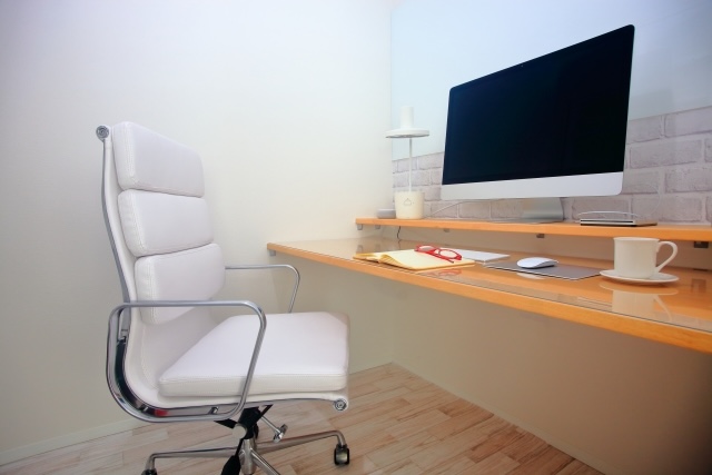 パソコンデスクの前に置かれた白いキャスター付きオフィスチェア