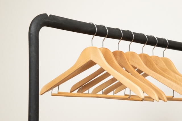 木製ハンガーだけが掛かった黒いハンガーラック