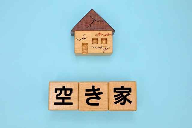 ひび割れた家と「空き家」の文字ブロック