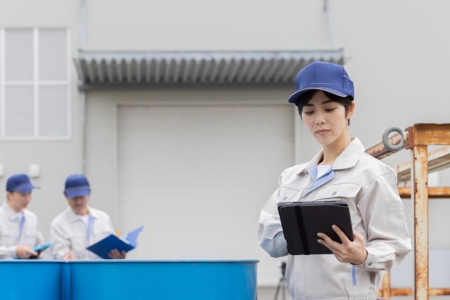 タブレットを操作する作業服の女性