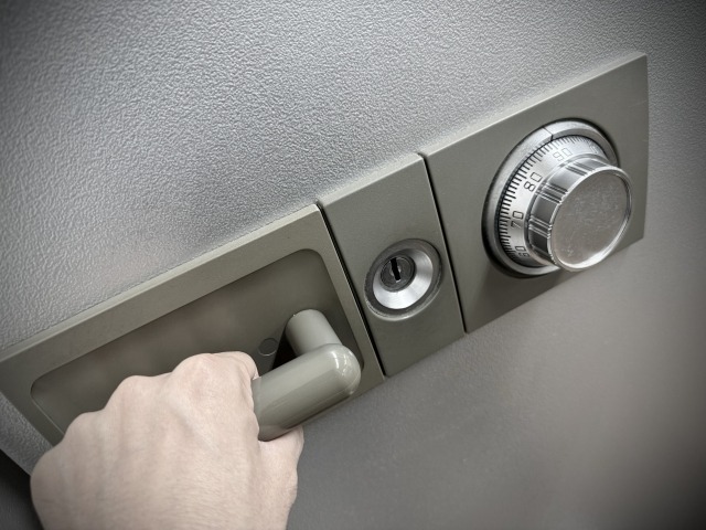 金庫のハンドルを握り開けようとする様子