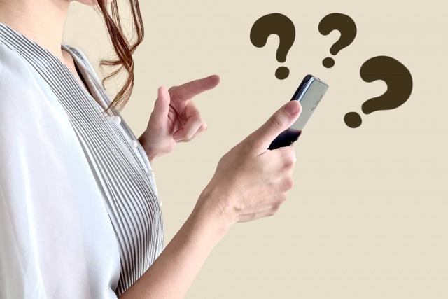 スマホを触る女性とクエスチョンマーク