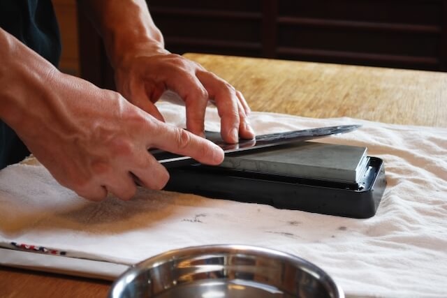 包丁を砥石で研ぐ職人の手元