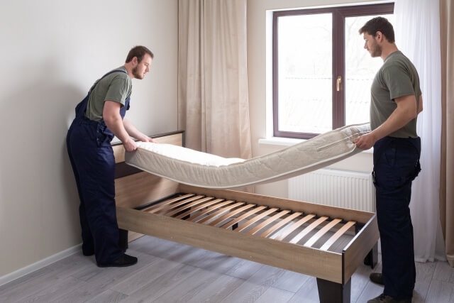 マットレスを運び出す2人の男性