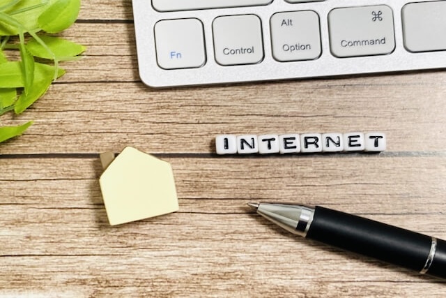 木製テーブルに置かれたキーボードとINTERNETブロックの画像