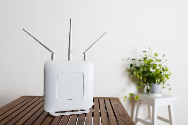 木製デスクに置かれた白い無線ルーターの画像