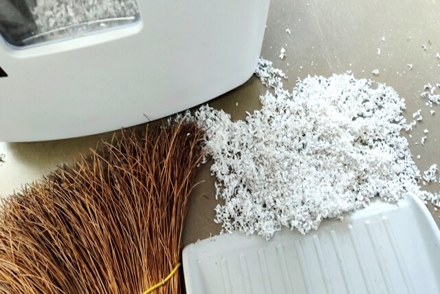 床に散らばったシュレッダーごみを掃除する様子の画像