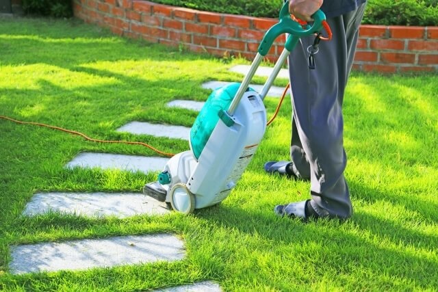 大型の芝刈り機で庭を手入れする様子