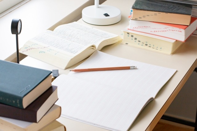 机にノートと書籍を広げて勉強する様子