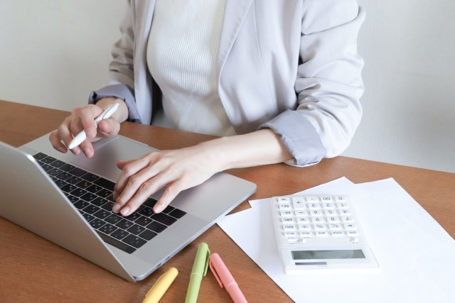 電卓を傍に置いてパソコンを操作する様子