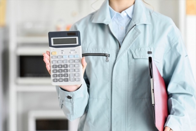 電卓を提示する作業着の女性