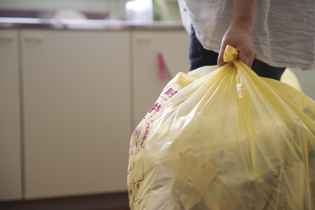 指定ごみ袋に入れてごみ出しする女性