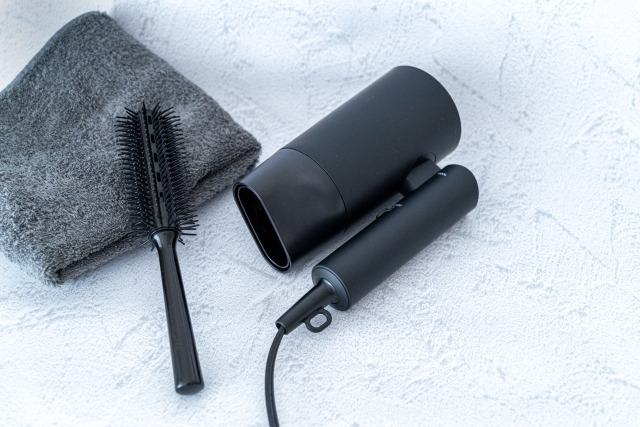 白いテーブルに置かれた黒いドライヤーとタオル