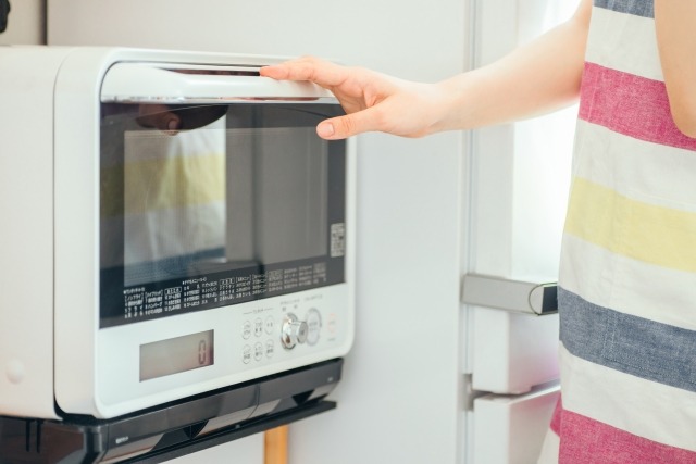 白い電子レンジを操作する女性