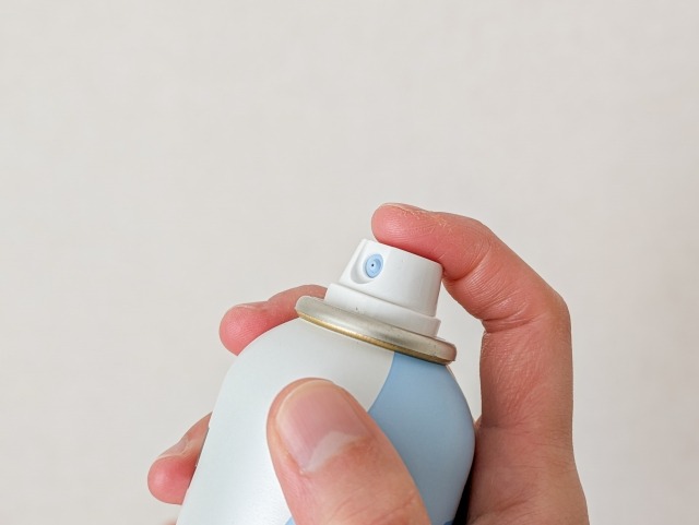 スプレー缶に指をかけて噴射する様子