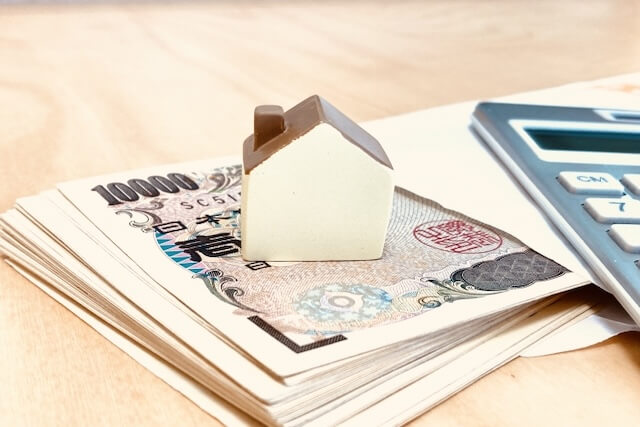 家のミニチュアと封筒に入った紙幣