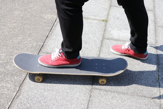 スケボーに片足を乗せる赤いスニーカーの男性