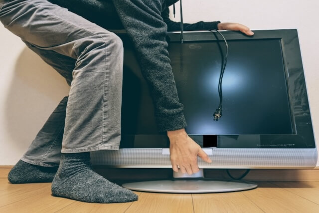 ALT：重いテレビを運ぼうとする様子