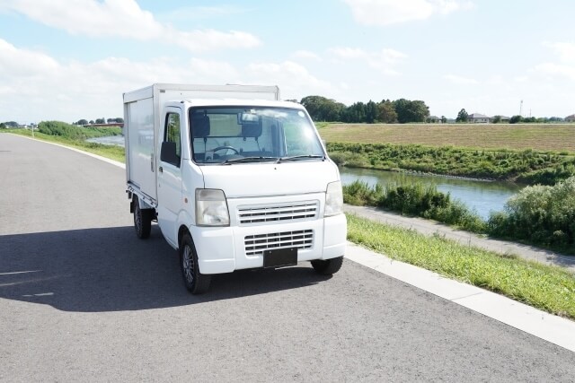 土手沿いを走る不用品回収の軽トラック