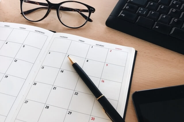 テーブルに広げたスケジュール帳とメガネ